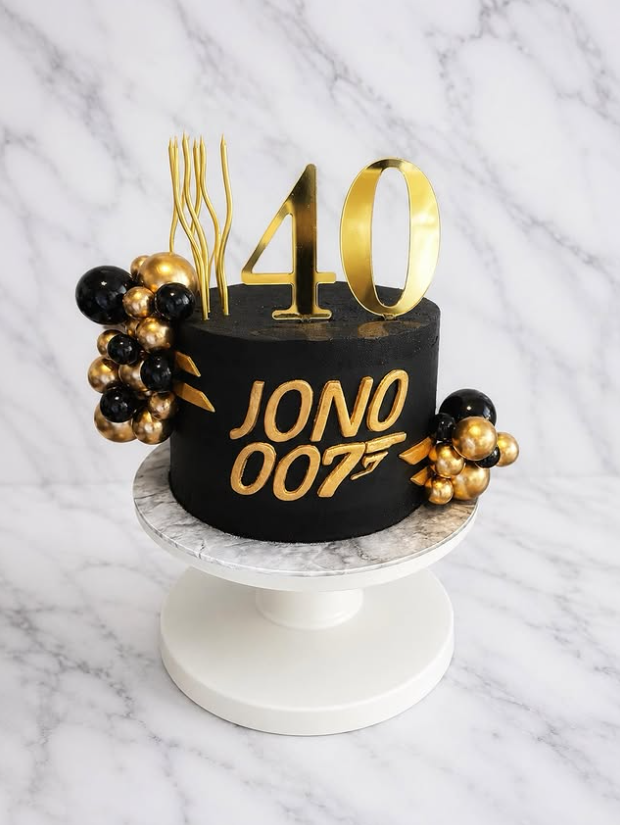 Black and gold JONO 007 themed 40th birthday cake with gold balloons