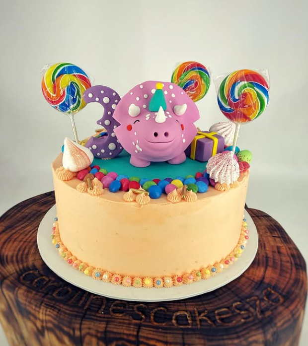 Peach buttercream cake with pink dragon, lollipops and sweets
